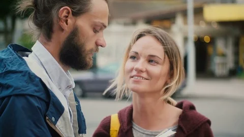 Portrait of young couple standing in the city centre and talking, reading the Stock Footage