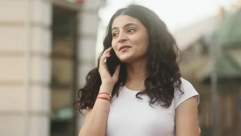 Portrait of young dark haired pretty woman having phone call at city Stock Footage 250478616
