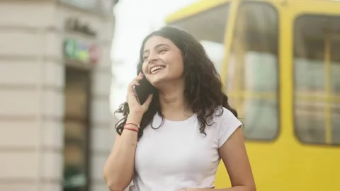 Portrait of young dark haired pretty woman having phone call at city Stock Footage 250480693