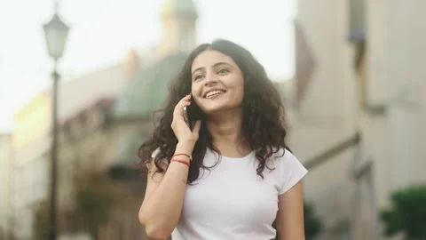 Portrait of young dark haired pretty woman having phone call at city Stock Footage 250480744