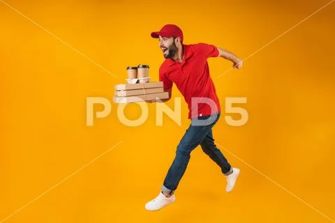 Portrait of young delivery man in red uniform running with pizza boxes and ta Stock Photos