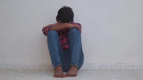 Portrait of a young depressed Indian kid crying while sitting alone.  Stock Footage