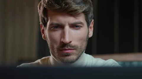 Portrait of a young developer working on a laptop, focused man looks at the Stock Footage 276890389