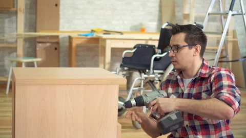 Portrait of a young disabled man next to a wheelchair collects a bedside table Stock Footage 105136774