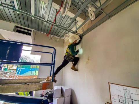 Portrait of young drylining contractor installing ceiling on construction site Stock Photos