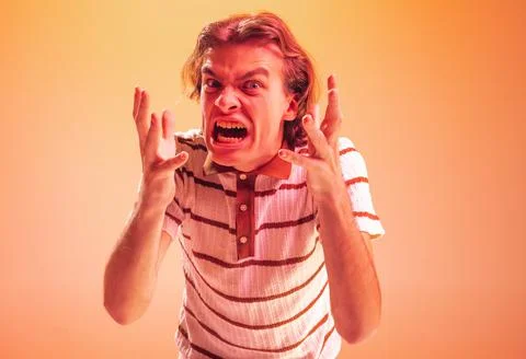 Portrait of young emotive man showing anger, irritation isolated over orange Stock Photos