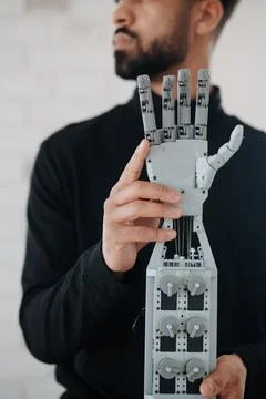 Portrait of young engineer holding robotic arm. Stock Photos