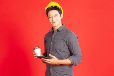 A portrait of a young engineer standing on a red background smiling and enjoy Stock Photos