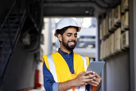 Portrait of young engineer worker, man in helmet and vest using tablet computer Stock Photos