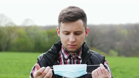 Portrait of a young farmer putting on a protective mask in a green field Stock Footage 130894763