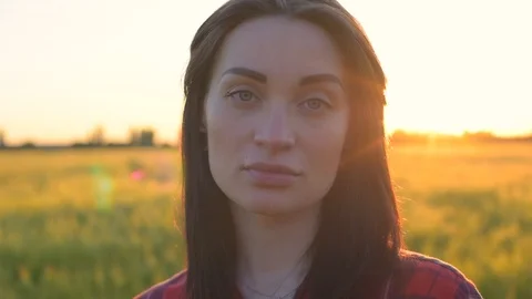 Portrait of young female looking at camera in wheat field during sunset Stock Footage 90082940