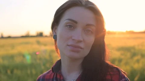 Portrait of young female looking at camera in wheat field during sunset Stock Footage 90083007