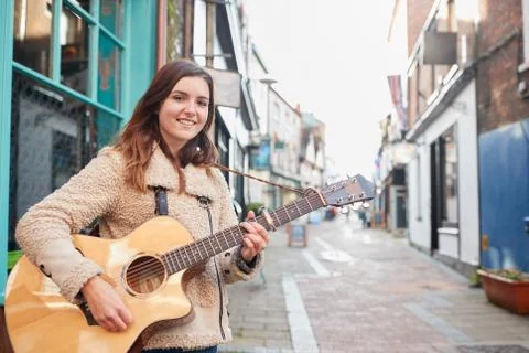 Portrait Of Young Female Musician Busking Playing Acoustic Guitar And Singing Stock Photos