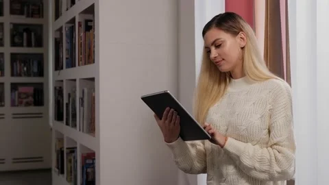 Portrait of a young female student in the library with a tablet. Stock Footage 145136342