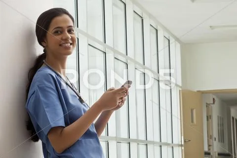 Portrait Of Young Female Surgeon Text Messaging On Cell Phone
