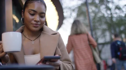 Portrait of young female using her phone at an outdoor cafe, with space for text Stock Footage 252417922