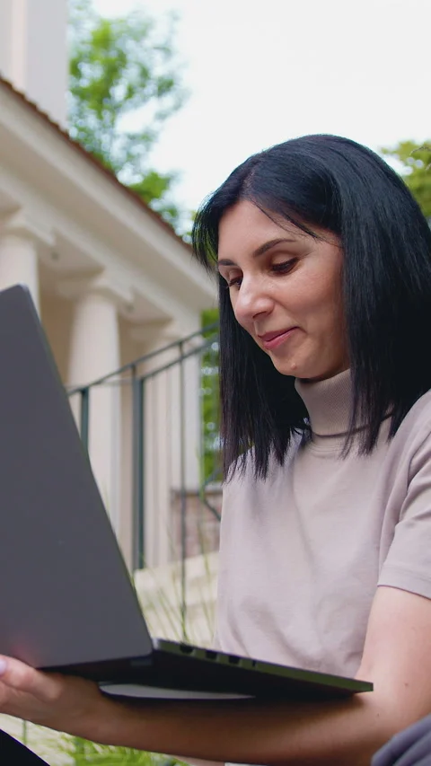 Portrait of young female worker typing on laptop while sitting on bench in park  Stock Footage 331676299