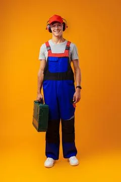 Portrait of young foreman worker with toolbox over yellow background Stock Photos