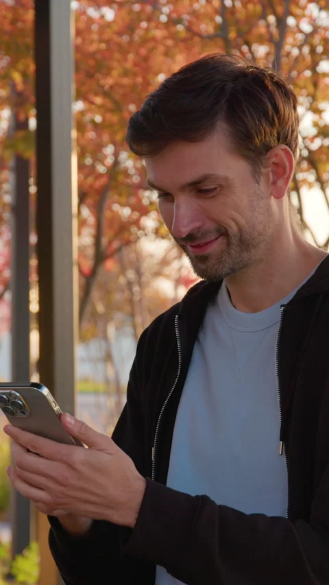 Portrait of a young freelancer man sitting on a bench outside in a sunset light Stock Footage 318475797
