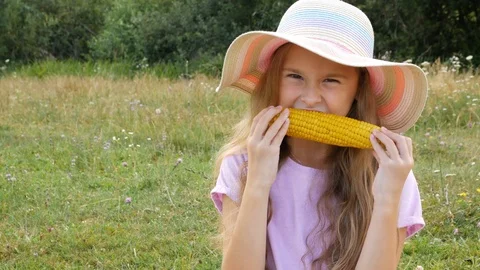 Portrait of a young girl deliciously biting corn. Yummy summertime Stock Footage