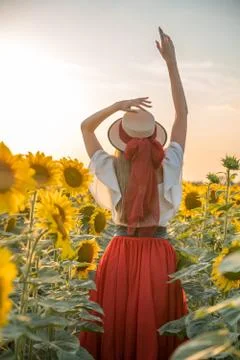 A portrait of a young girl that is standing back to camera in sunflower field. Stock-Fotos