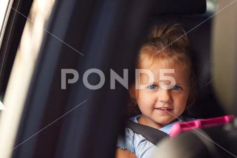 Portrait Of Young Girl Watching Digital Tablet In Back Seat On Car Journey Stock Photos