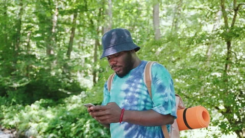 Portrait young guy in forest looking in smartphone hiking near river. Stock Footage 246494711