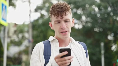 Portrait of a young guy holding a phone in his hands on the street Video stock 167303690