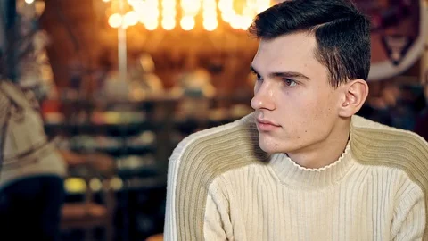 A portrait of a young guy looking around in a cozy coffee shop. Vídeo Stock 108296100