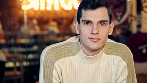 A portrait of a young guy looking around in a cozy coffee shop Video stock 108296290