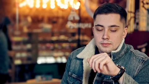 A portrait of a young guy looking around in a cozy coffee shop. Video stock 108297686