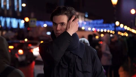 Portrait of young guy looking at camera standing at night in city street Stock Footage 83629525