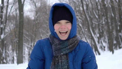 Portrait of a young guy in the winter forest and laughs, snow falls Stock Footage 100654503