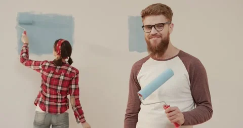 Portrait of young handsome man standing with paint roller in his hands and Stock Footage 144628984