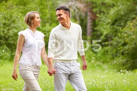 Portrait of young happy couple walking in summer park Stock Photos