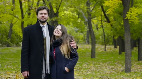Portrait of a young happy couple wearing coats in the autumn park Stock Footage 59797578