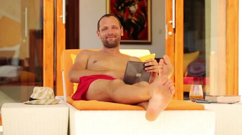 Portrait of young, happy man with tablet lying on sunbed in luxury villa HD Stock Footage 40398128