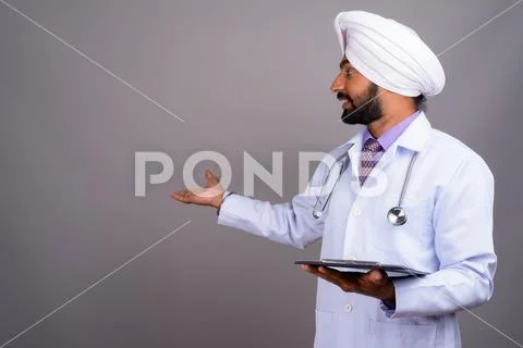 Portrait of young Indian Sikh man doctor holding clipboard Stock Photos