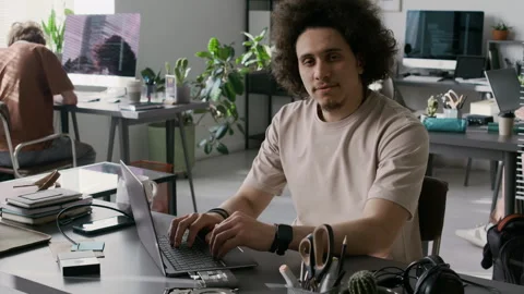 Portrait of Young Male Developer Coding on Laptop and Looking at Camera Stock Footage 299204181