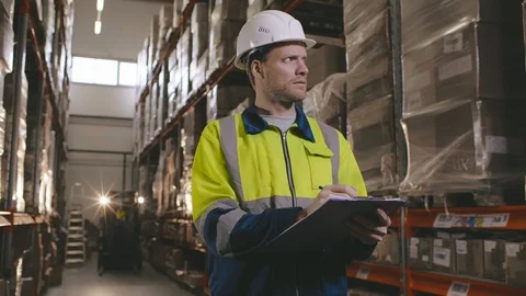 Portrait of young male manager checking stocks on clipboard in warehouse. Video stock 123280174