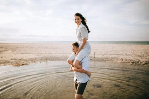 Portrait of young man and young woman on morning sea beach. Summer vacation c Stock Photos
