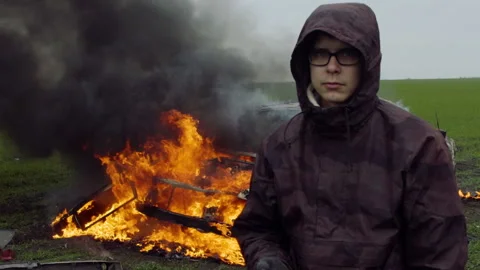 Portrait of a young man on the background of a burning car, car crash Stock Footage 95186365