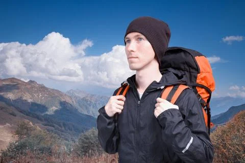 Portrait of young man with backpack on the background of a mountain landscape Stock Photos