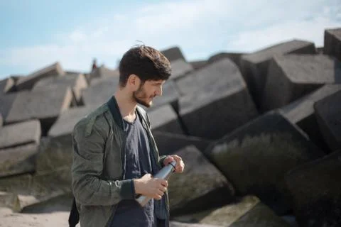 Portrait of young man with backpack, using reusable steel thermo water bottle. Stock Photos