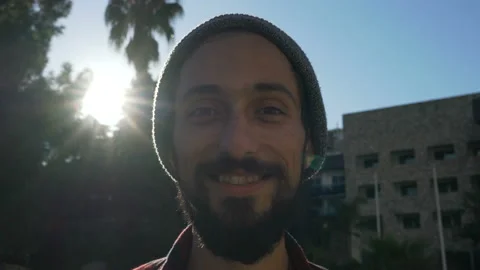 Portrait of a young man with a beard in a hat who is smiling while looking at Video stock 120347432