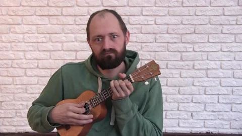 Portrait of a young man with a beard playing the ukulele Stock Footage 131381035