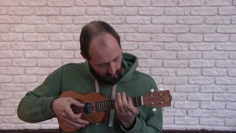 Portrait of a young man with a beard playing the ukulele Video stock 131381090