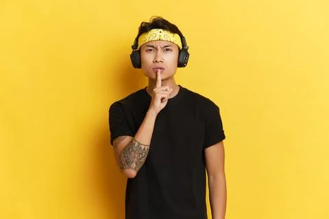 Portrait of young man in black Tshirt and headphones with yellow headnand on Foto stock