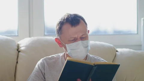 Portrait of a young man with a book reading while sitting on a sofa against the Stock Footage 128322902