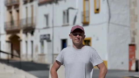 Portrait of a young man in a cap, stands on a bright sunny day on the street Video stock 120996004